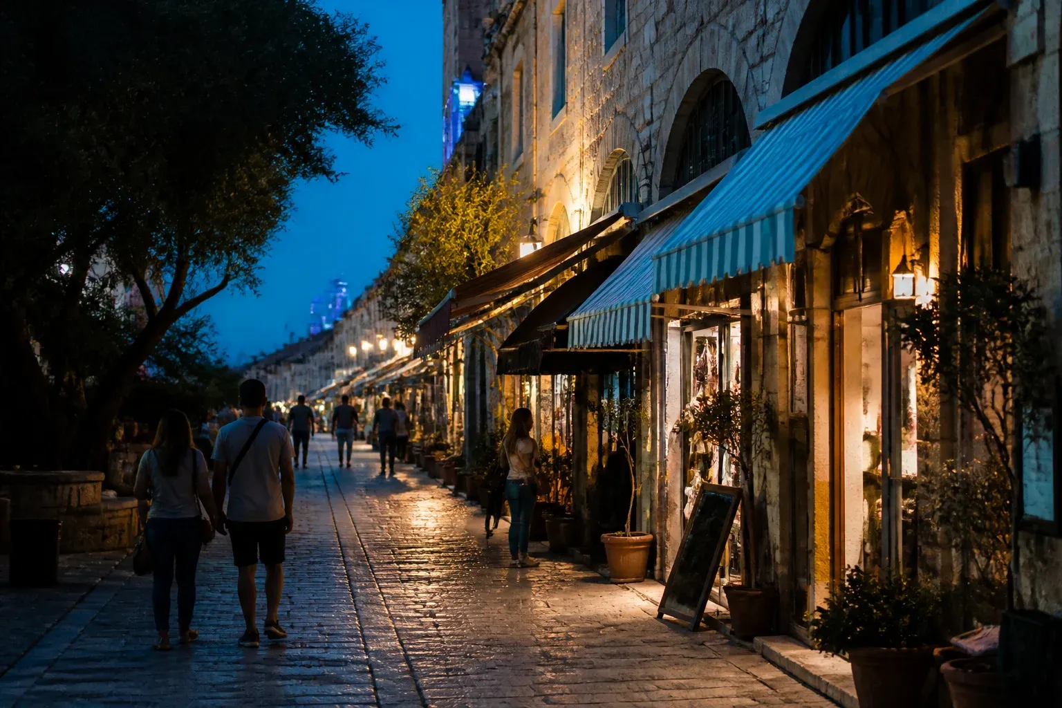שורת חנויות עם סככות בד בסמטה להולכי רגל ביפו בשעת בין ערביים